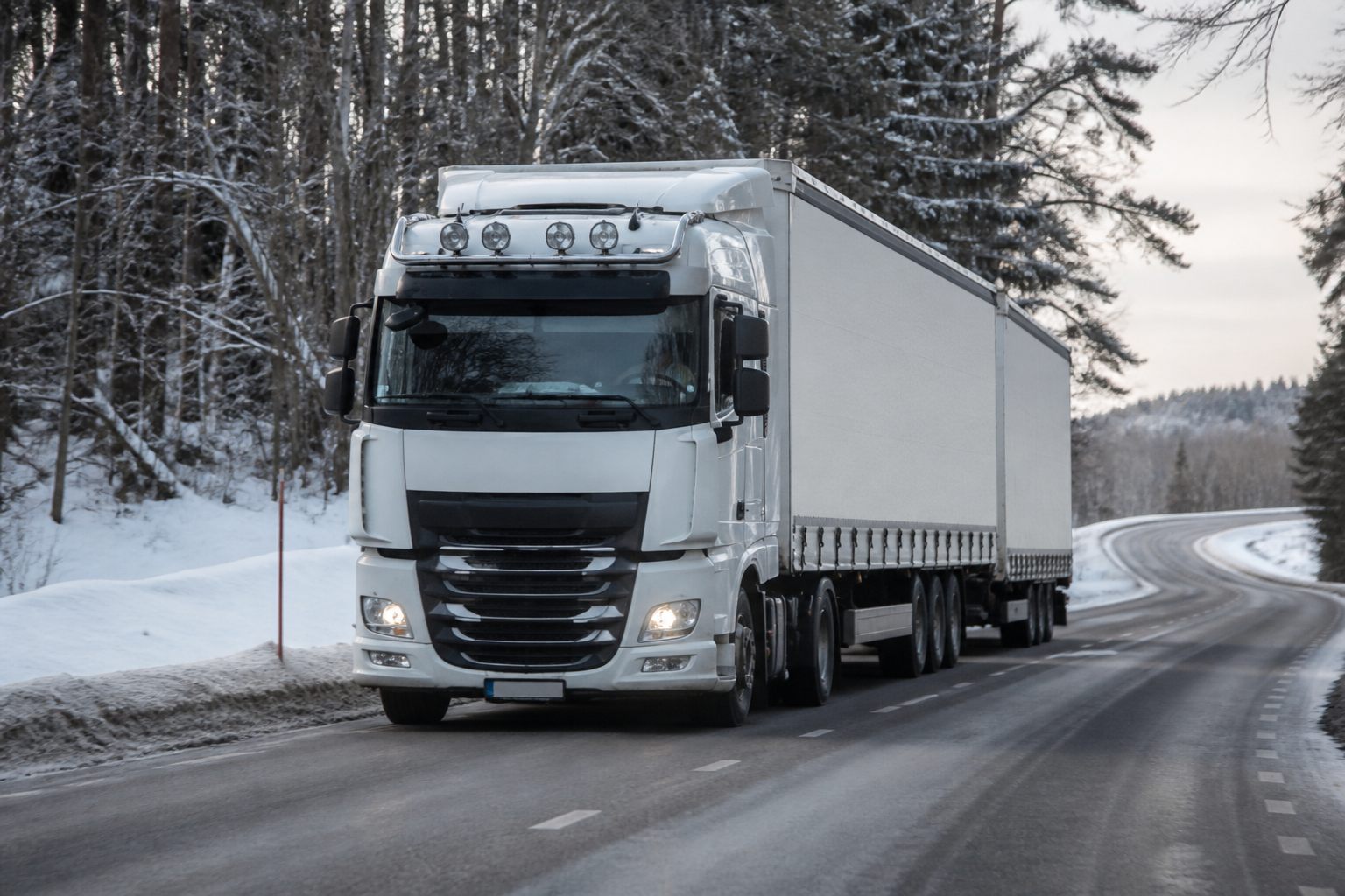 HGV driving on a winter road with snow at the verges